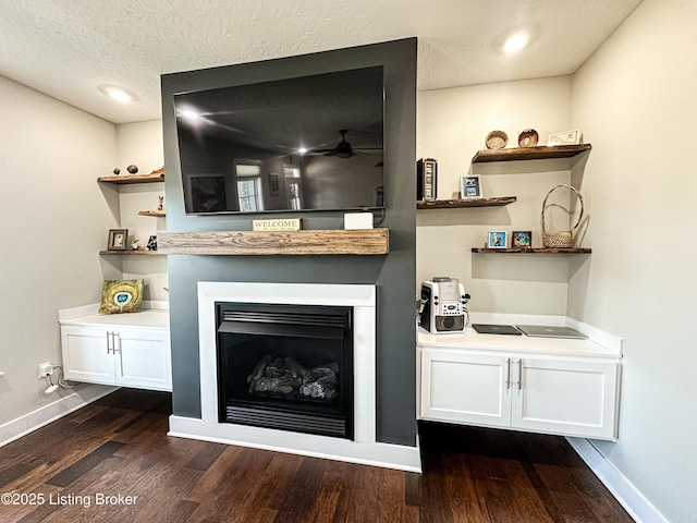 interior space featuring dark wood-style floors, a fireplace, baseboards, and a textured ceiling