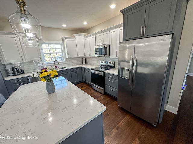 kitchen featuring appliances with stainless steel finishes, dark wood finished floors, a sink, and decorative backsplash