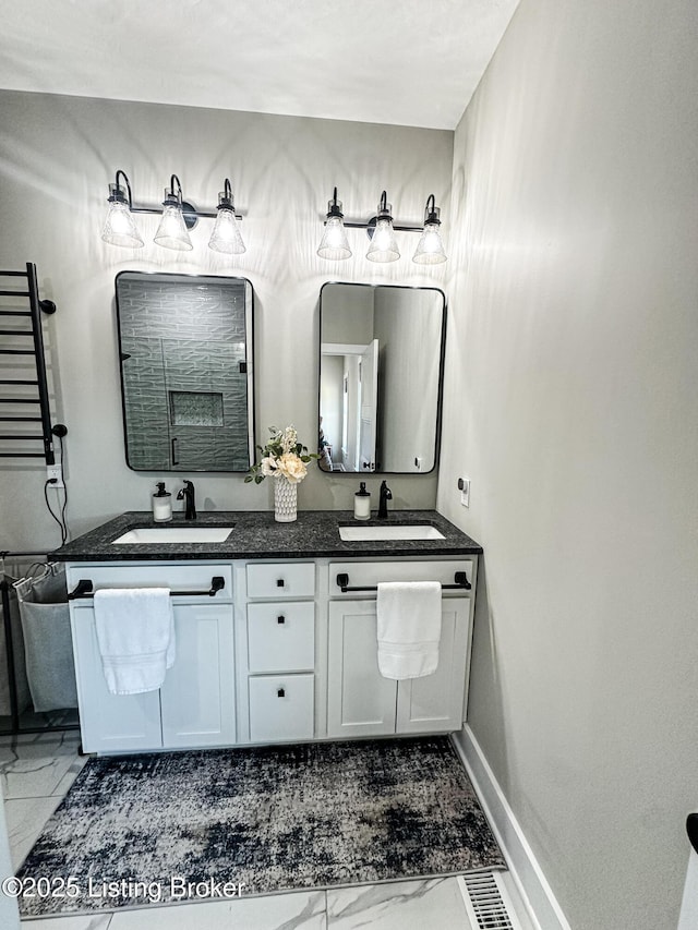 bathroom with double vanity, marble finish floor, baseboards, and a sink