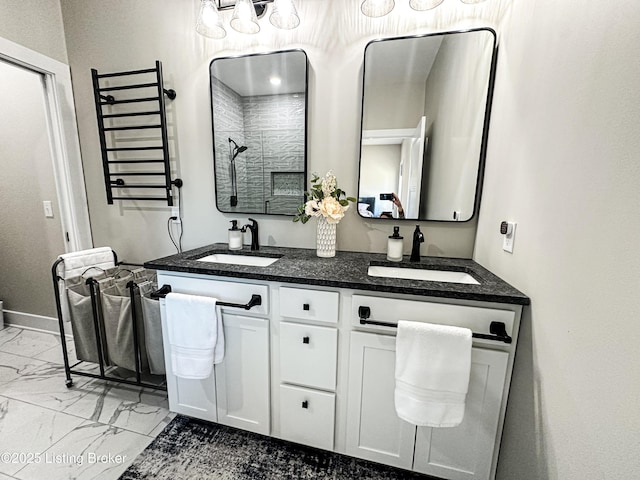 bathroom featuring marble finish floor, double vanity, walk in shower, and a sink