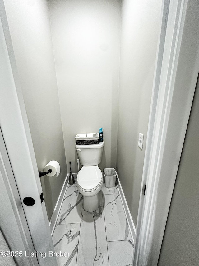 bathroom featuring toilet, marble finish floor, and baseboards