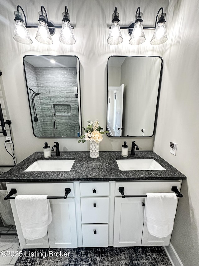 full bath featuring a sink, a shower stall, baseboards, and double vanity