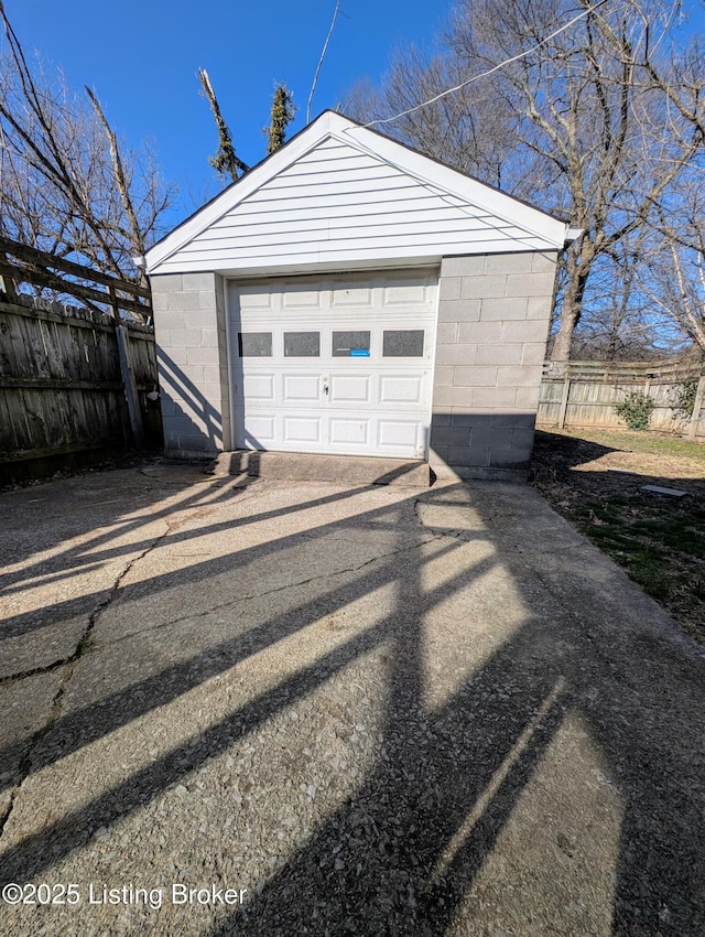 detached garage featuring fence and driveway