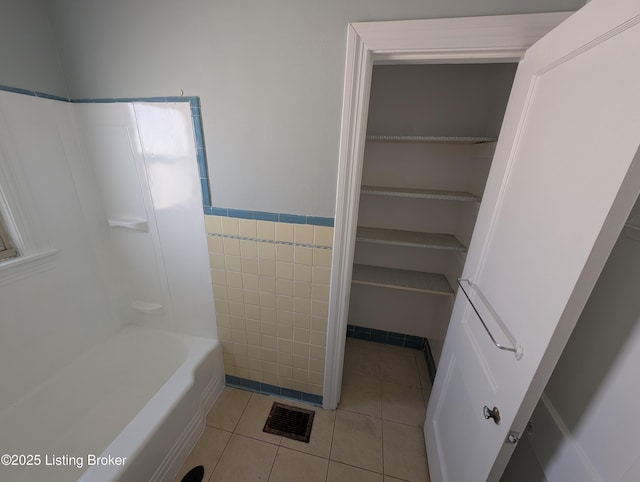 bathroom with tile patterned floors, visible vents, tile walls, and a wainscoted wall