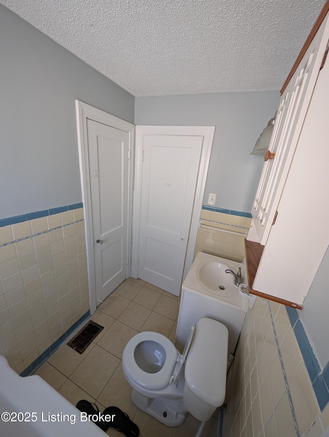 bathroom featuring visible vents, a textured ceiling, tile walls, and tile patterned flooring