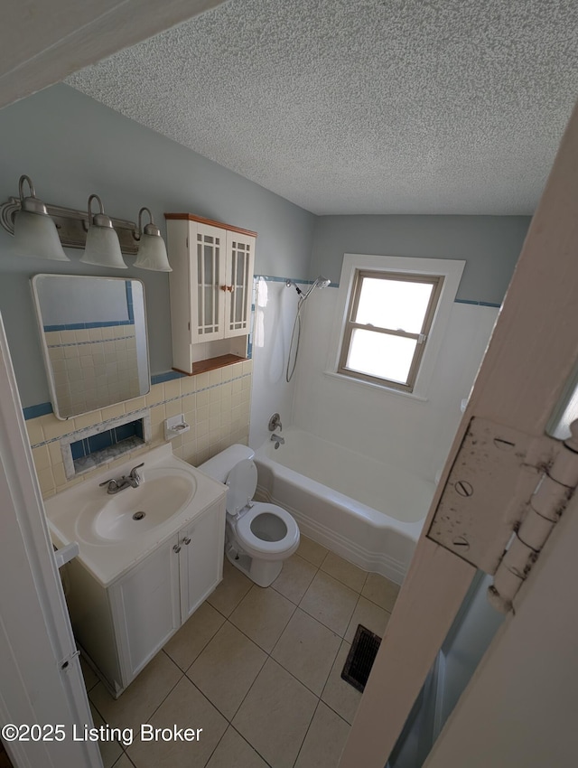 bathroom featuring tub / shower combination, tile walls, vanity, tile patterned floors, and a textured ceiling