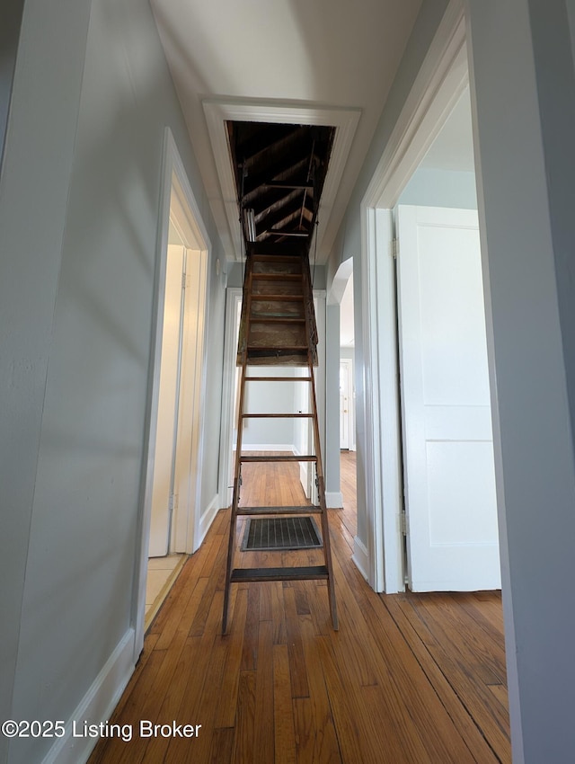 corridor with baseboards and hardwood / wood-style floors