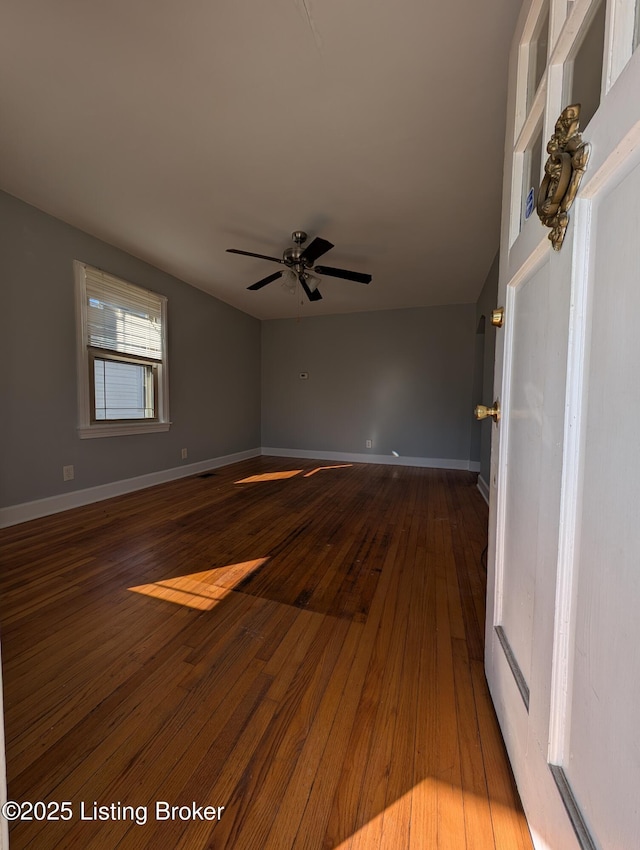 unfurnished room with dark wood-style floors, ceiling fan, and baseboards