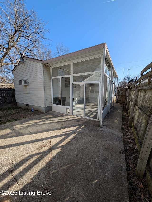 back of house with a wall mounted air conditioner, crawl space, a fenced backyard, and a sunroom