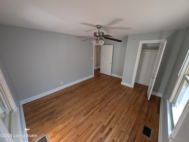 unfurnished bedroom featuring visible vents, baseboards, a closet, and hardwood / wood-style floors