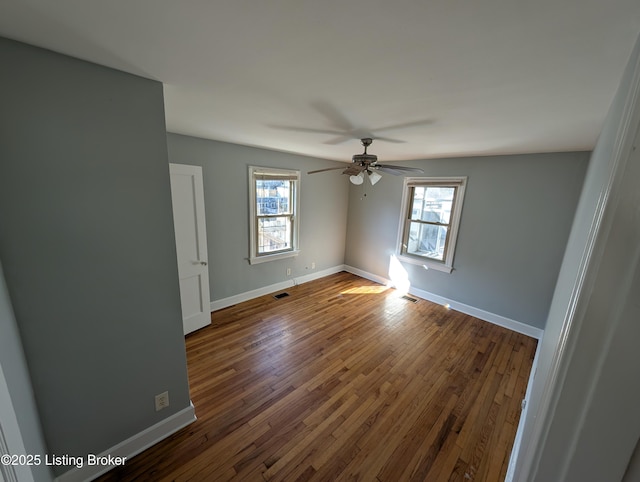 spare room featuring hardwood / wood-style floors, baseboards, visible vents, and ceiling fan