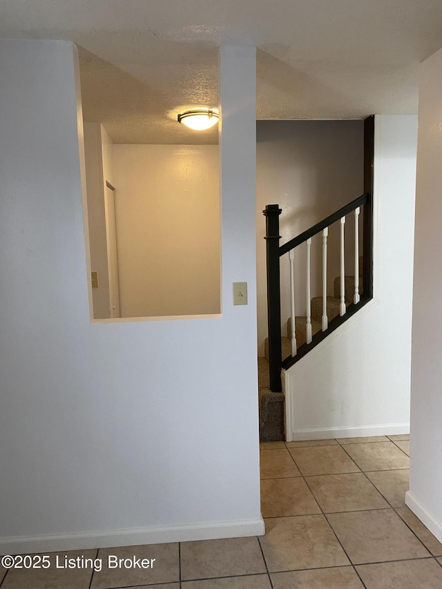 stairs featuring tile patterned flooring, a textured ceiling, and baseboards