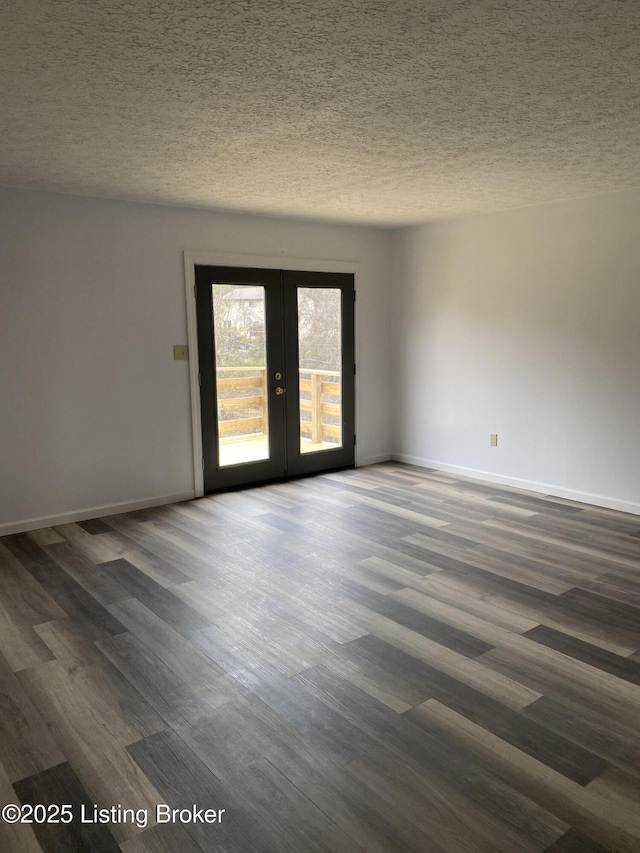 empty room with french doors, a textured ceiling, dark wood-type flooring, and baseboards