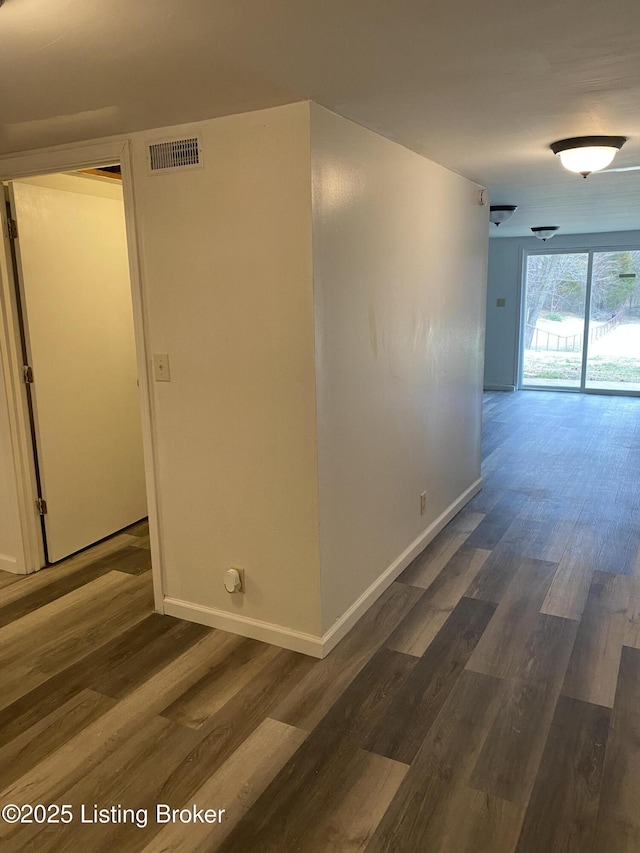 hallway featuring visible vents, baseboards, and dark wood finished floors