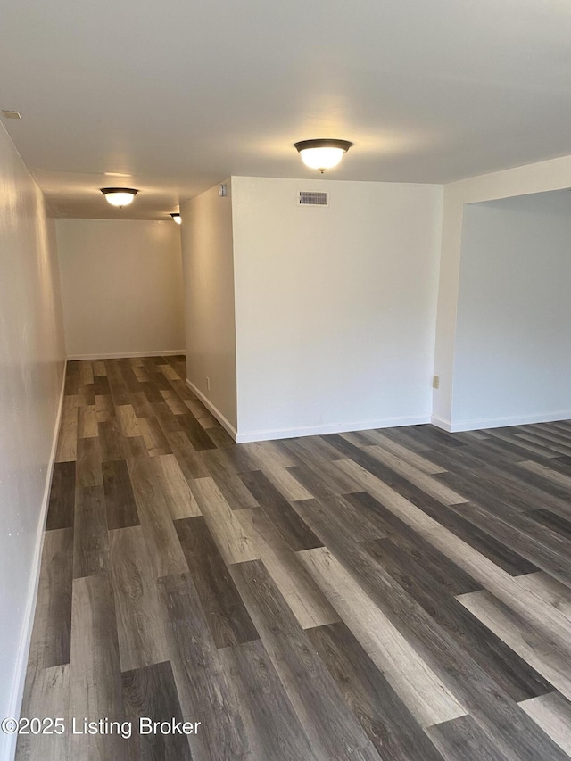 interior space with baseboards, visible vents, and dark wood-style flooring