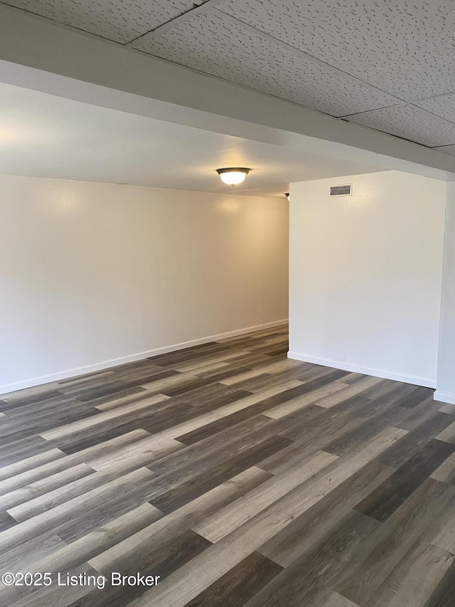 empty room featuring dark wood-style floors, visible vents, and baseboards