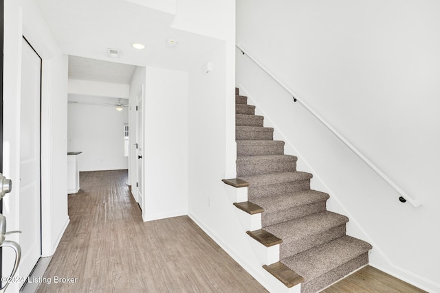 staircase featuring baseboards, visible vents, a ceiling fan, and wood finished floors