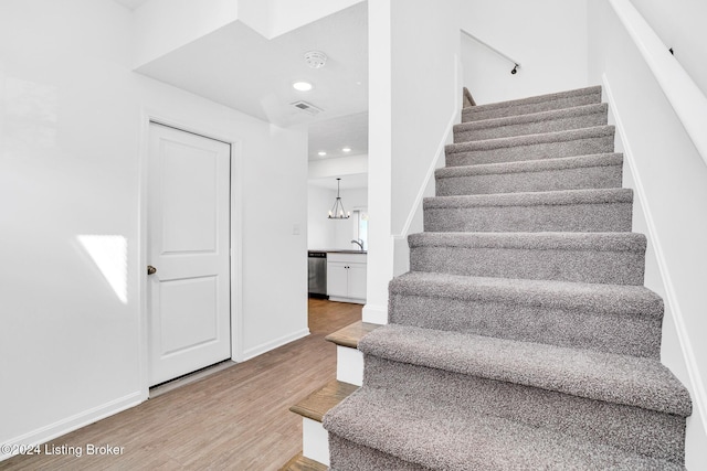 staircase featuring baseboards, visible vents, wood finished floors, and recessed lighting