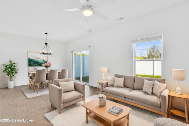 living room featuring light wood finished floors, visible vents, and ceiling fan with notable chandelier