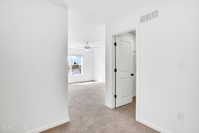 corridor with a textured ceiling, carpet, visible vents, and baseboards