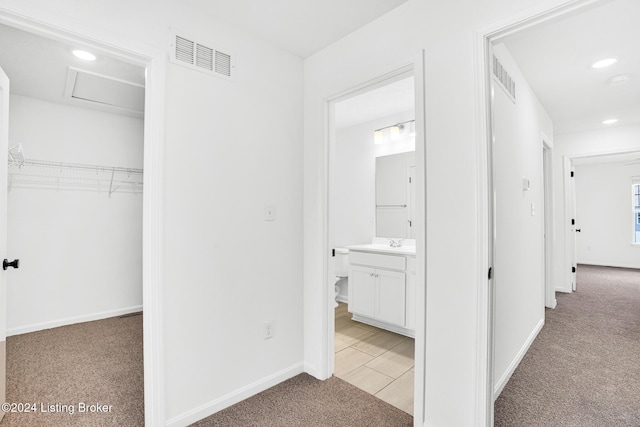 hall with attic access, light carpet, visible vents, and baseboards