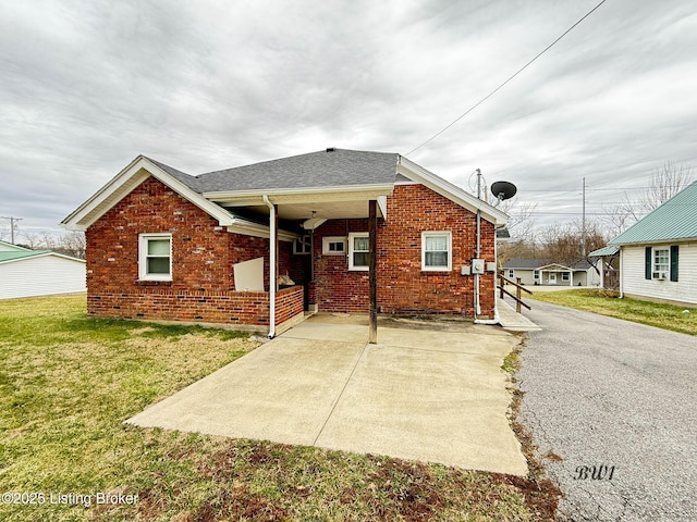 back of property featuring a yard, brick siding, and a shingled roof