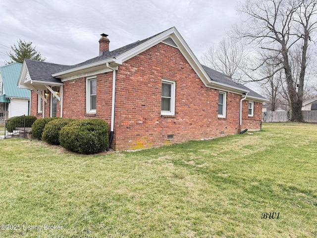 view of side of property with a lawn, a chimney, crawl space, fence, and brick siding