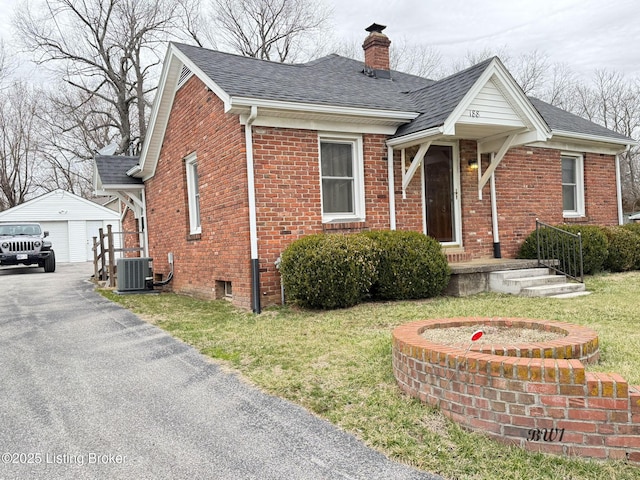 bungalow-style home featuring a shingled roof, a chimney, a detached garage, an outdoor structure, and brick siding