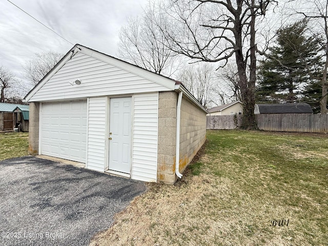 view of outbuilding with driveway, an outdoor structure, and fence