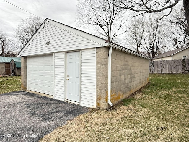 view of outbuilding featuring fence, aphalt driveway, and an outdoor structure