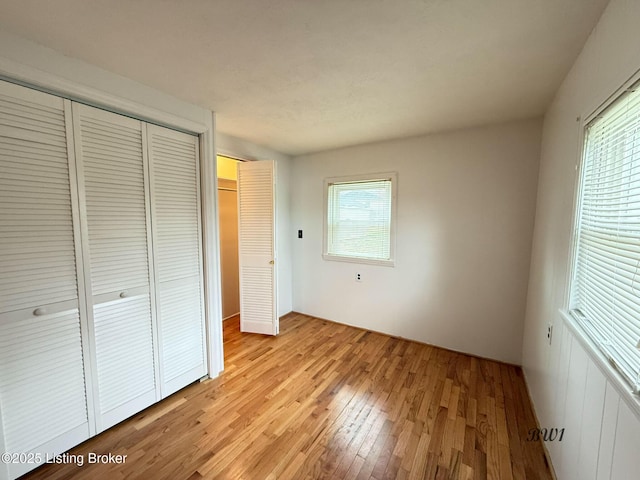 unfurnished bedroom with light wood finished floors and a closet