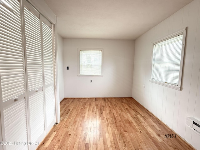 unfurnished bedroom featuring a baseboard heating unit and light wood-style floors