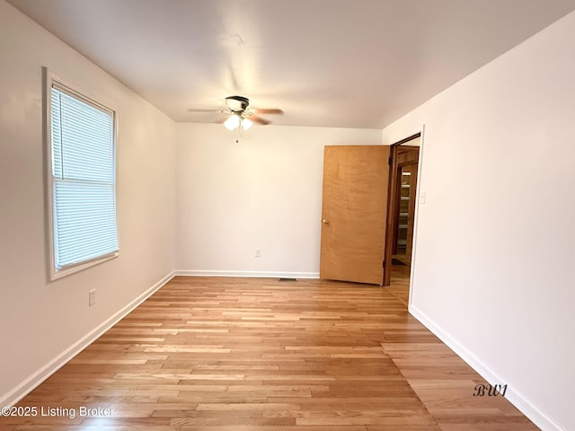 empty room featuring ceiling fan, light wood-style flooring, and baseboards