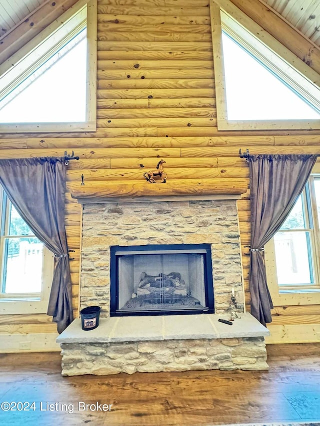 room details featuring log walls, a stone fireplace, and wood finished floors