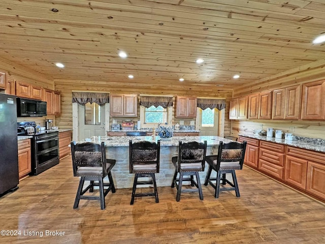 kitchen with wooden ceiling, black appliances, a breakfast bar, and light wood-style floors