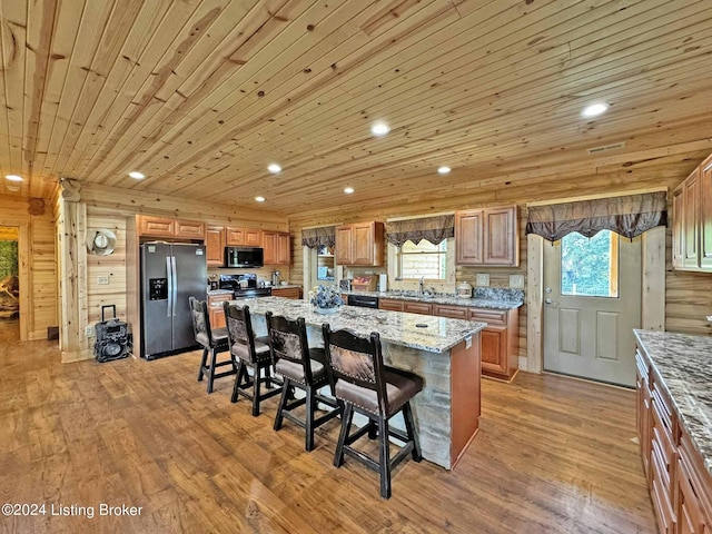 kitchen featuring recessed lighting, stainless steel appliances, a sink, a kitchen breakfast bar, and light wood finished floors