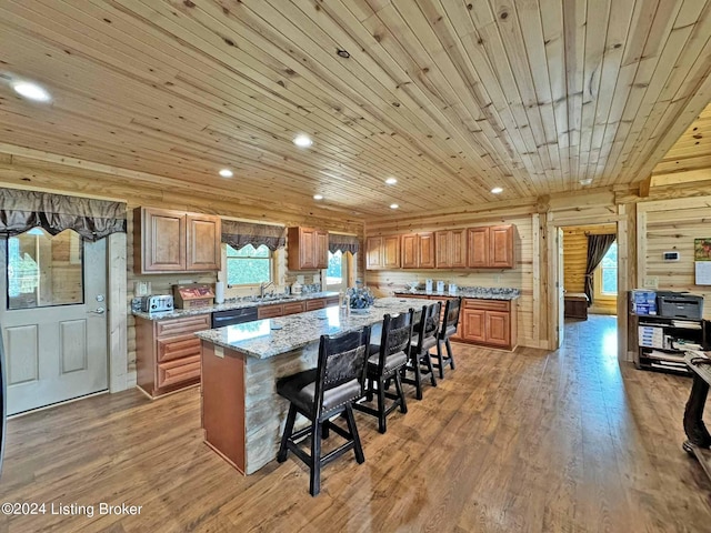 kitchen featuring wooden ceiling, a breakfast bar, a sink, stainless steel dishwasher, and light wood finished floors