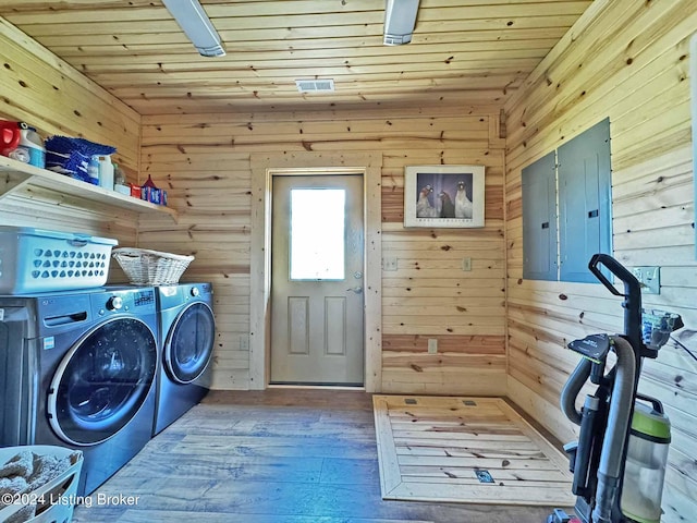 washroom featuring wood walls, washer and dryer, laundry area, electric panel, and hardwood / wood-style flooring