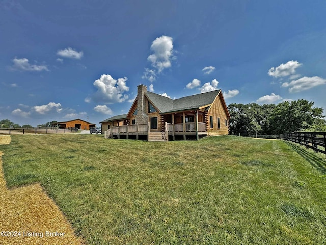 back of house featuring a yard, a chimney, fence, a deck, and log siding