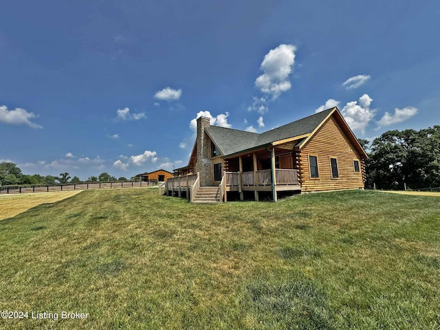 rear view of property featuring a chimney, log siding, a yard, fence, and a wooden deck