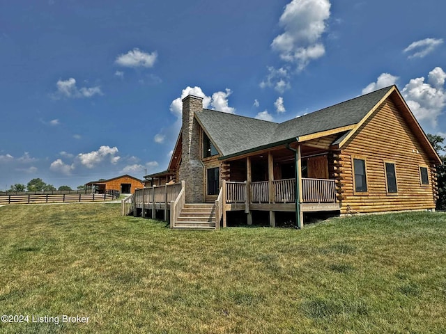 rear view of property featuring a yard, a chimney, log siding, and fence