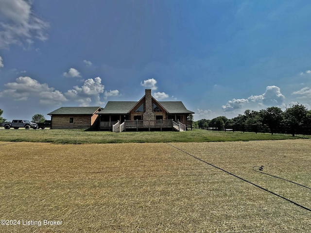 view of front facade featuring a wooden deck, a chimney, and a front yard