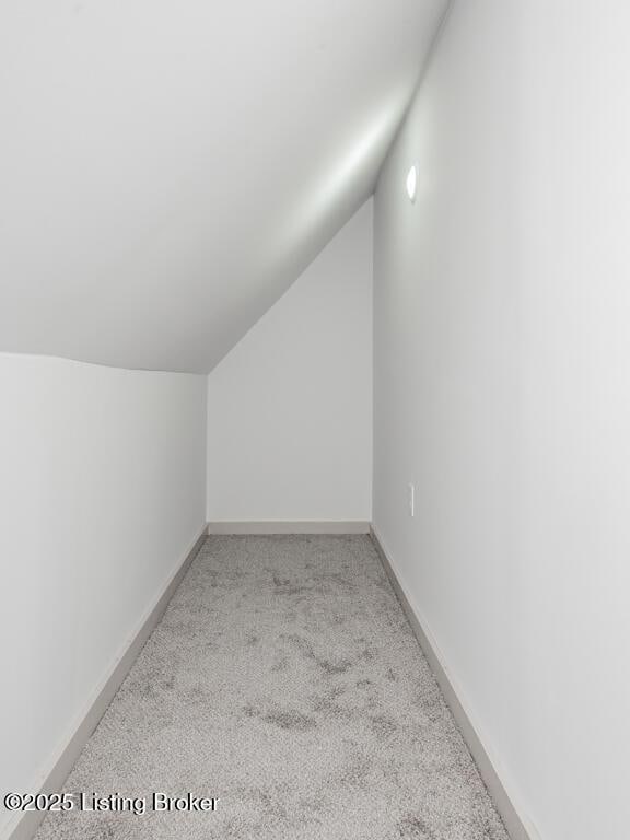 bonus room with lofted ceiling, light colored carpet, and baseboards