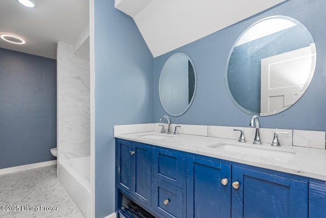 bathroom featuring double vanity, toilet, baseboards, and a sink