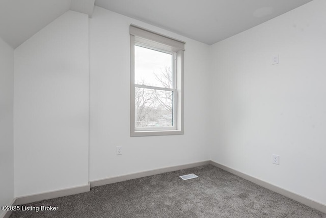 empty room with visible vents, baseboards, carpet flooring, and vaulted ceiling