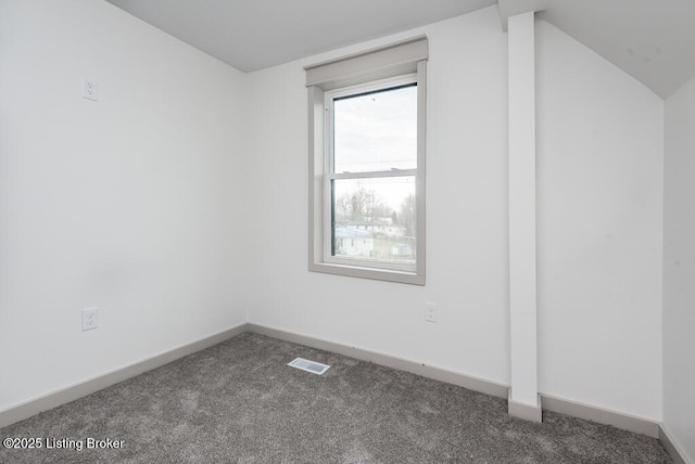 unfurnished room featuring dark colored carpet, visible vents, baseboards, and vaulted ceiling