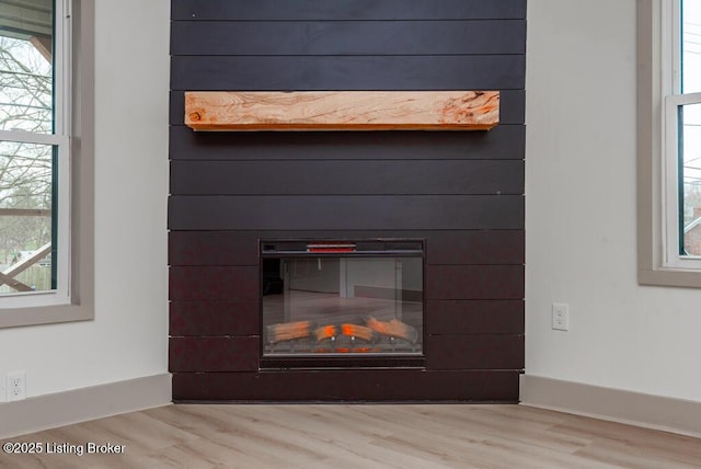 details with baseboards, wood finished floors, and a glass covered fireplace