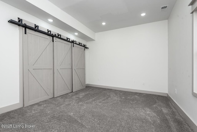 interior space featuring visible vents, carpet floors, baseboards, recessed lighting, and a barn door