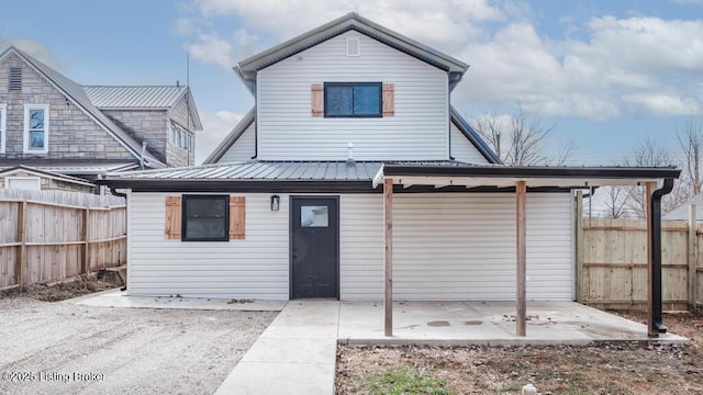 rear view of property featuring metal roof, fence, and a patio area