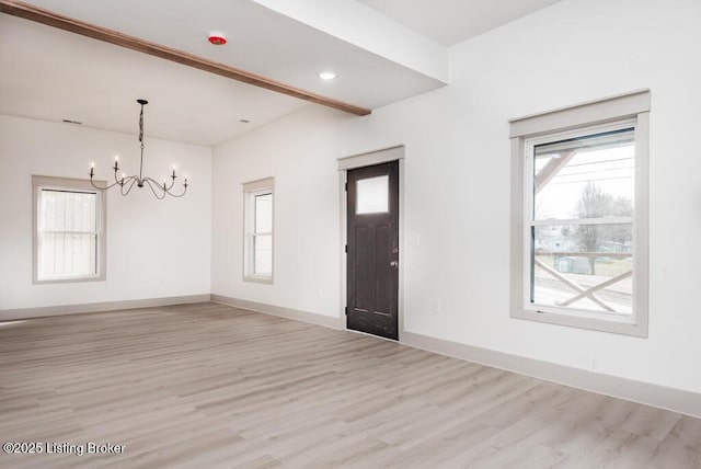 foyer with a wealth of natural light, a chandelier, light wood-type flooring, and baseboards